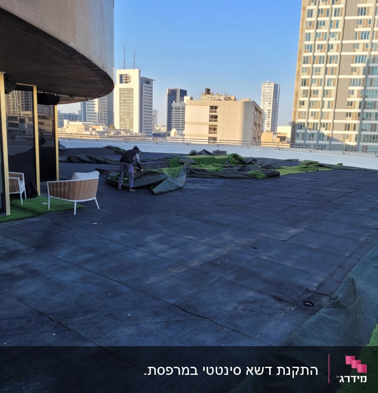 אדם פורש יריעות דשא מלאכותי על גג